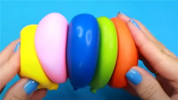 В руках держат пять разноцветных шариков, наполненных сыпучим веществом. Шарики прилипли другу к другу