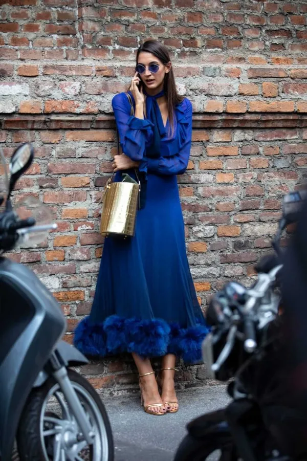 Синее платье с меховой окантовкой и золотистые босоножки создают единый гармоничный наряд.