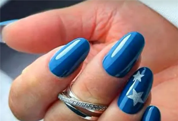 Ногти средней длины овальной формы, покрытые синим лаком и украшенные рисунками звезд