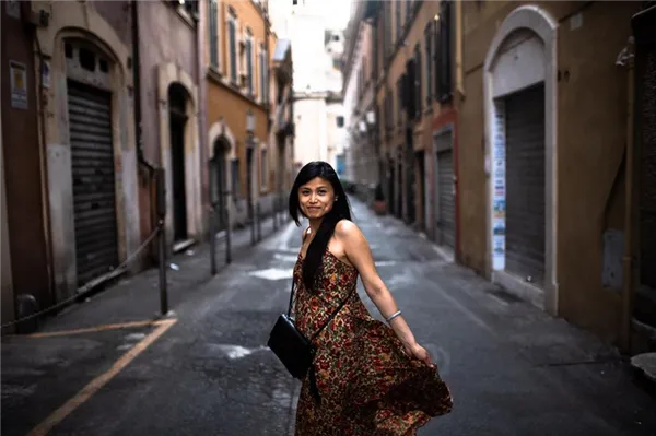 Девушка в длинном платье на фоне городской улочки